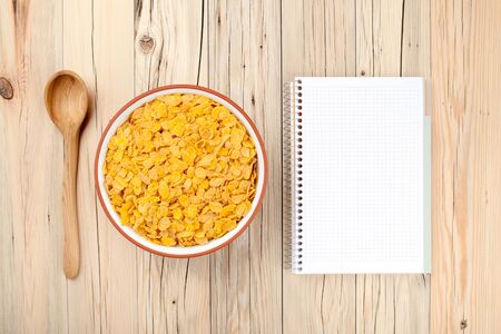 Cornflakes and notebook on wooden backgroundの写真素材