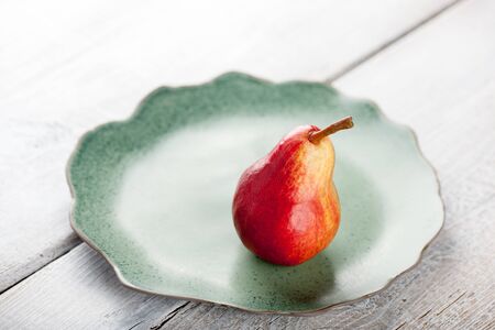 Ripe pear on the green plate on wooden tableの写真素材