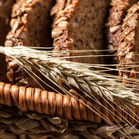 Sliced rye bread with seeds in the basket on a wooden table, close upの写真素材