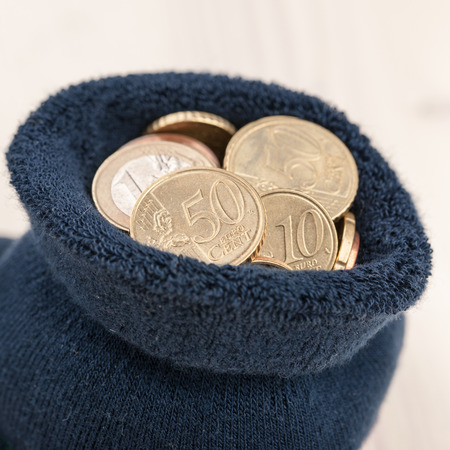 Euro coins in the sock and on wooden tableの写真素材