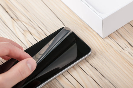 Man's hand unpacking a new smartphone, close-up