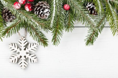 Christmas fir decorated and decorative snowflake on light wooden backgroundの写真素材