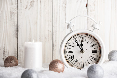 Christmas and New Year card with vintage alarm clock, Christmas balls and candle on wooden...