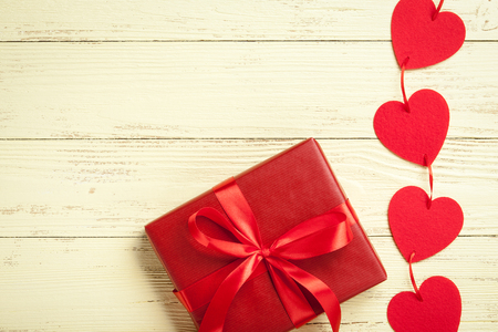 Red hearts and gift box on yellow wooden backgroundの写真素材