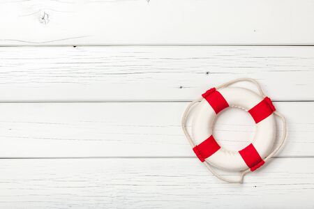 Red-white lifebuoy on white wooden boardの写真素材