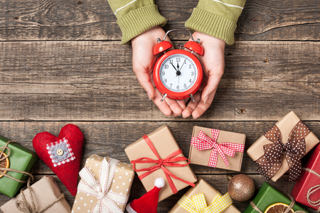 Christmas and New Year eve background with gift boxes, christmas decorations and alarm clock in handsの写真素材