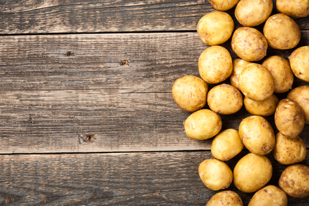 Raw potato on wooden tableの写真素材