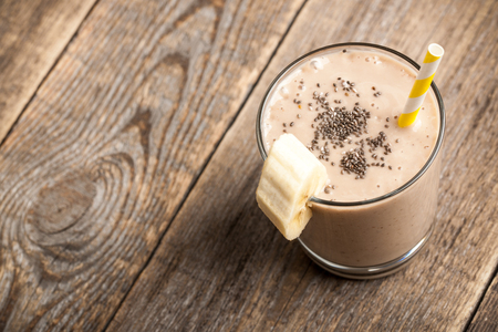 Banana chocolate smoothie glass on wooden tableの写真素材