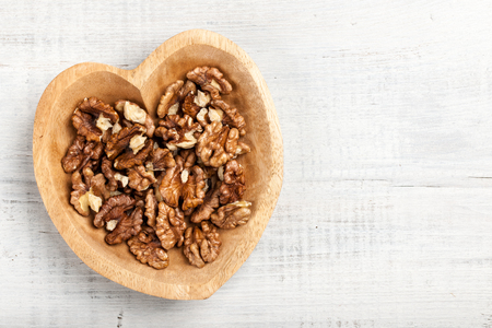 Walnuts in heart shaped wooden bowlの写真素材