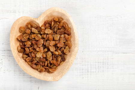Raisins in heart shaped wooden bowlの写真素材