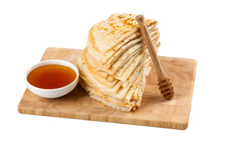 Homemade pancakes and honey on wooden cutting board on white background