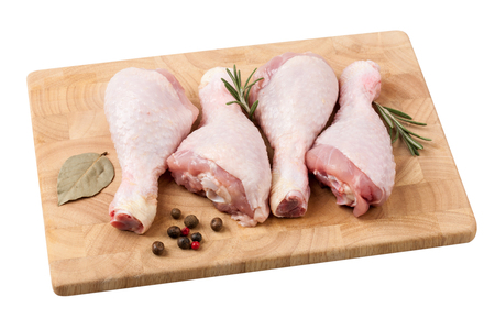 Raw chicken legs on wooden board on whiteの写真素材