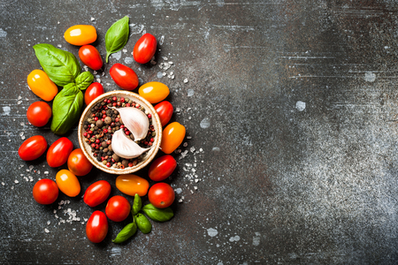 Red and yellow fresh cherry tomatoes and spices on vintage tableの写真素材