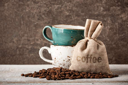 Coffee beans and cups on wooden tableの写真素材