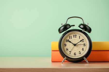Stack of books and alarm clock on wooden tableの写真素材