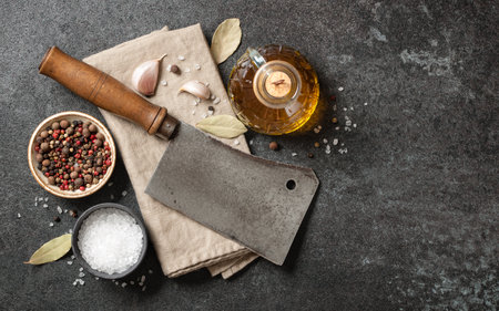 Vintage butcher cleaver and spices for cooking on kitchen tableの写真素材