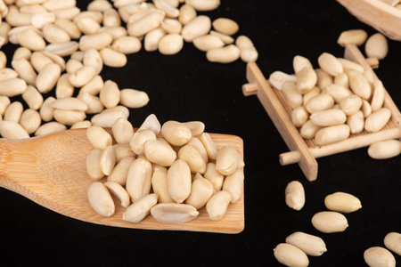 Pine nuts on a wooden spoon on a black background close up