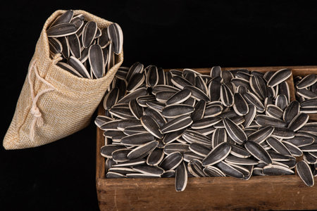 Sunflower seeds in a wooden box on a black background closeup