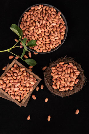 Raw Organic Peanuts on a Black Background in a Bowl and a Cup
