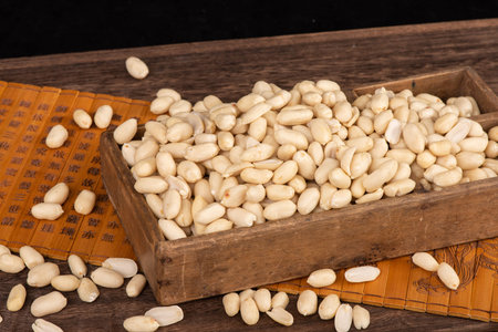 Pine nuts in a wooden box on a dark wooden background.