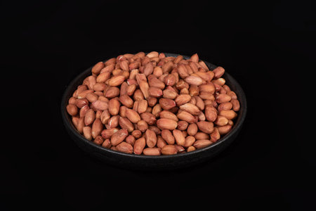 Peanuts in a bowl on a black background. Close up.