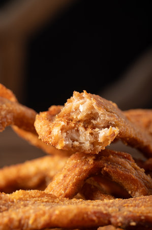 close up of fried chicken nuggets on a wooden table with black background