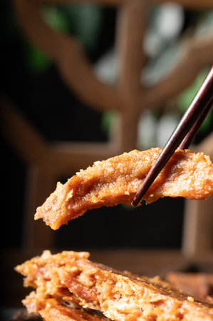 chopsticks picking up a piece of fried pork in a restaurantの写真素材