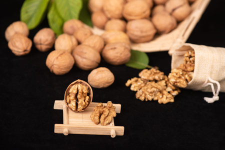 Walnut kernels and whole walnuts on a black background with leaves
