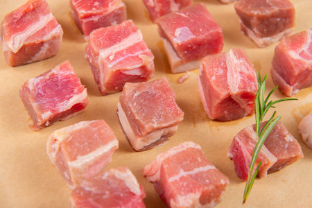 Pieces of raw pork with rosemary on a baking sheet.の写真素材