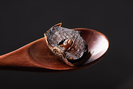 Dried persimmon on a wooden spoon on a black backgroundの写真素材