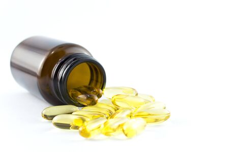 Fish oil capsules in a glass bottle on white background, healthy Vitamin supplementation conceptの写真素材
