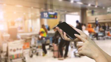 Hands holding smartphone. Airport terminal backgroundの写真素材