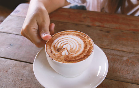 woman hand holding cup of coffee while resting in the cafe