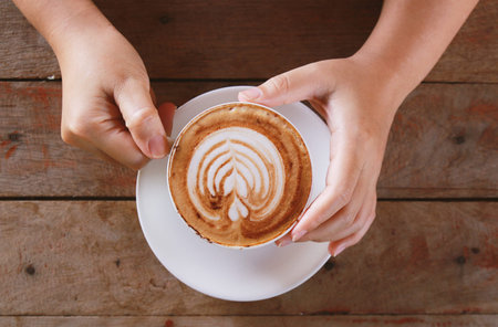 woman hand holding cup of coffee while resting in the cafe,top view