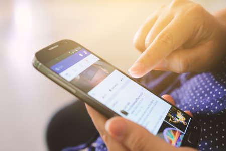 CHIANG MAI,THAILAND - November 15,2016: Female Holding Smartphone On Hand And Watching Facebook Timeline.のeditorial素材
