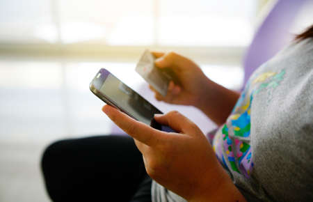 Woman holding a credit card and using smartphone for online shopping. Internet online payment with credit card.                                           の写真素材