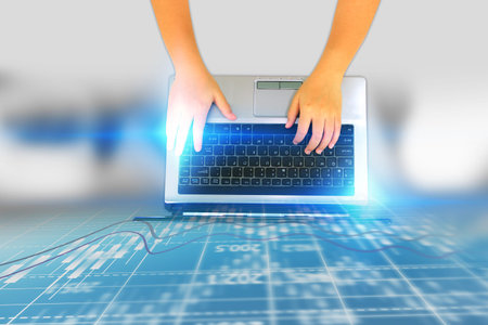 Businessman using laptop with stock exchange chart on screen.