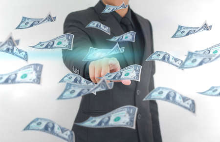 Businessman touching dollar banknotes flying in the air. Finance and earning conceptの写真素材