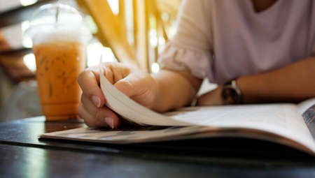 Young woman reading a book in cafe.                               の写真素材