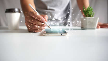 Hand using smartphone, icons interface on screen, creativity                      の写真素材