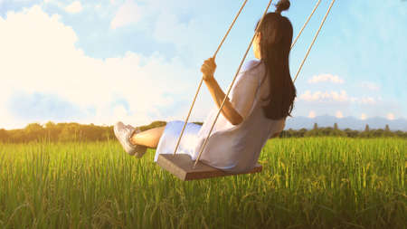 Girl on swing in sunlight.の写真素材