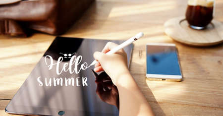 young woman writing "hello summer" on tabletの写真素材