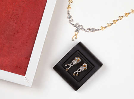 Beautiful diamond earring, golden necklace with diamond and part of flame isolated on white background.の写真素材