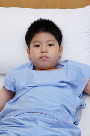 Young boy wear patient suit  in hospital bedの写真素材
