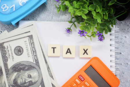 Business and economy concept with usd banknote with tax wording on notebook.