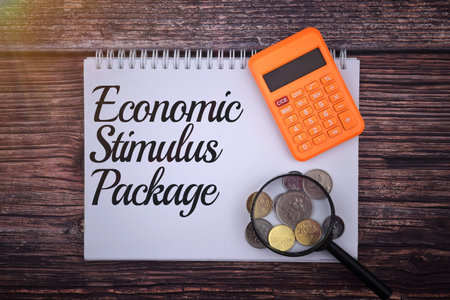 Economic Stimulus Package wording with calculator, magnifying glass and coin on a wooden background. Business and economy conceptの写真素材