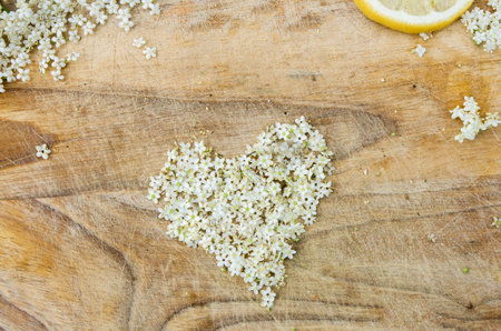 preparation of elderberry juice, ingredients of elderflower and lemon, preparation on the old table, wooden background, flowers in the shape of a heartの写真素材