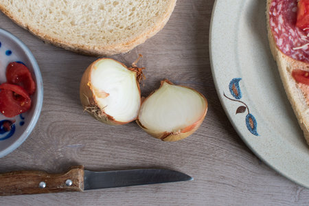 bread with salami and cheese, with onions on a wooden table, knife with onions