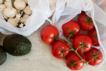 Fresh organic tomatoes from farm in eco friendly bag. Zero waste food shopping. Groceries in eco...