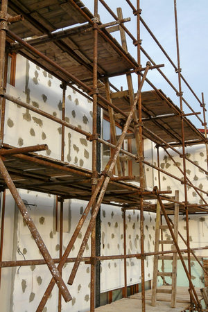 Thermal insulation of house wall with polystyrene. Picture of a scaffolding near familyhouse,...